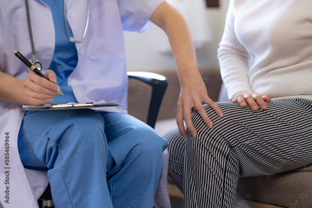 Female doctor examining the knee of an elderly Asian female patient. Female doctor examining the knee of an elderly Asian female patient.