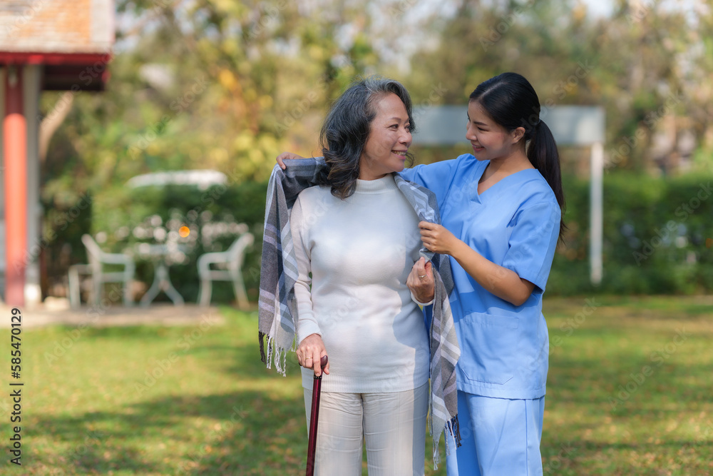 Asian nurse or female caregiver helping senior woman holding cane to walk in the hospital garden. Asian nurse or female caregiver helping senior woman holding cane to walk in the hospital garden.