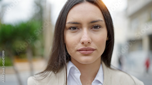 Young beautiful hispanic woman standing with serious expression at street