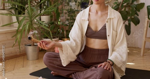 woman prepare her room for meditation using palo santo. close up cropped slow motion, girl treats pain and stress, clear negative energy. Ceremony