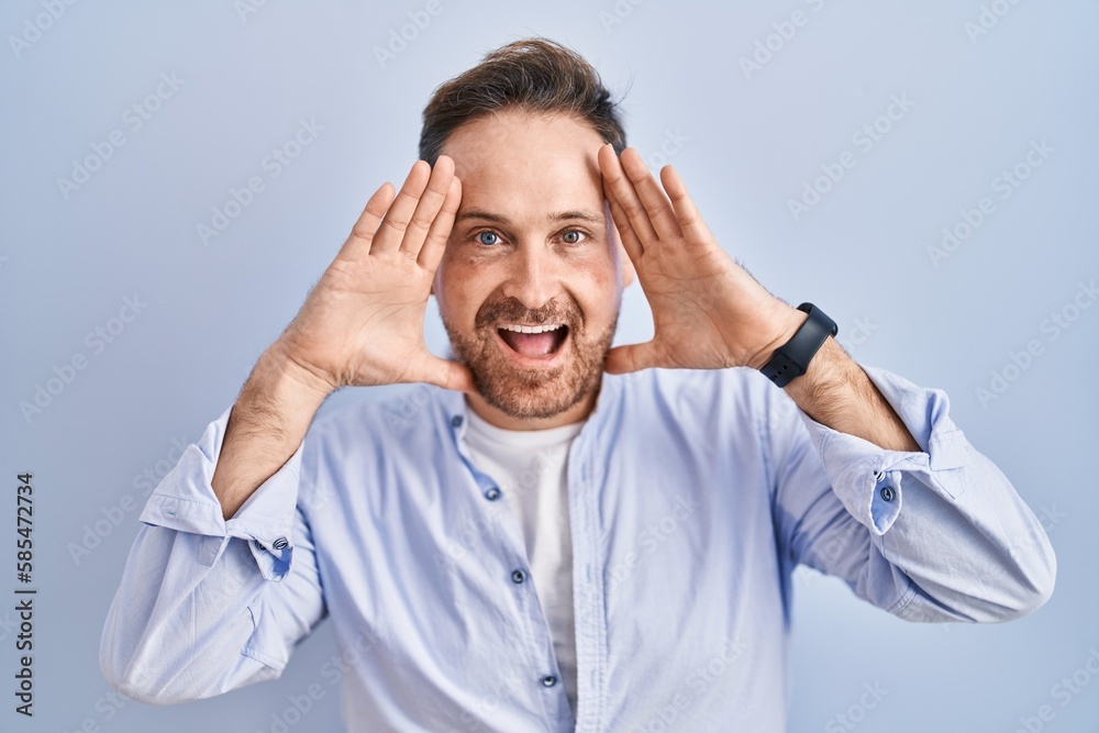 Naklejka premium Middle age caucasian man standing over blue background smiling cheerful playing peek a boo with hands showing face. surprised and exited