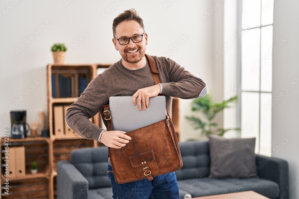 Young caucasian man business worker holding laptop of briefcase at office