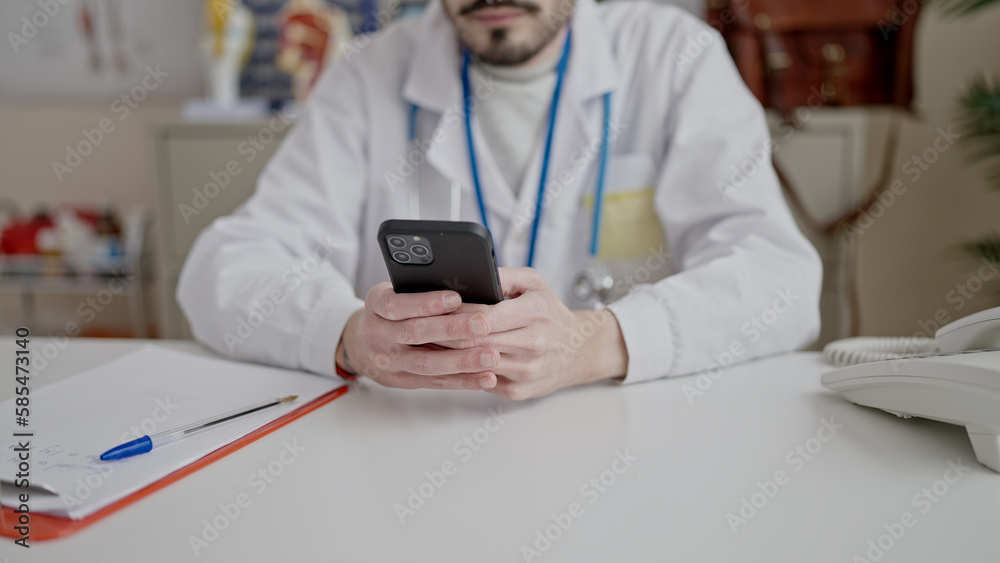 Young hispanic man doctor using smartphone working at clinic