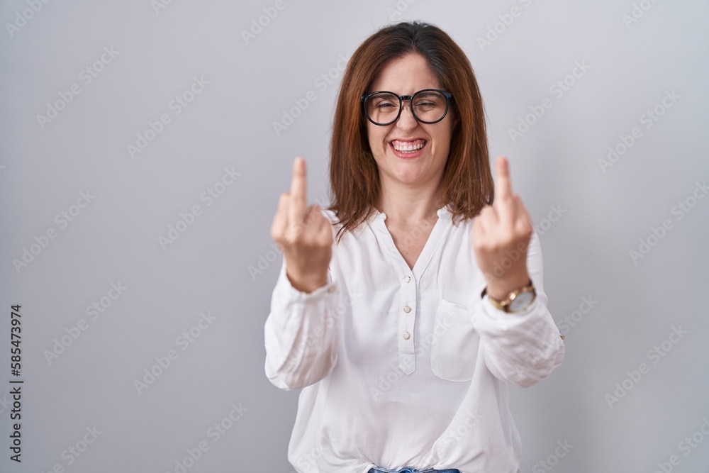 Brunette woman standing over white isolated background showing middle finger doing fuck you bad expression, provocation and rude attitude. screaming excited Brunette woman standing over white isolated background showing middle finger doing fuck you bad expression, provocation and rude attitude. screaming excited