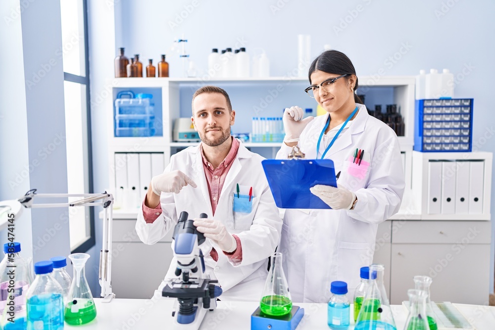 Two young people working at scientist laboratory pointing finger to one self smiling happy and proud Two young people working at scientist laboratory pointing finger to one self smiling happy and proud