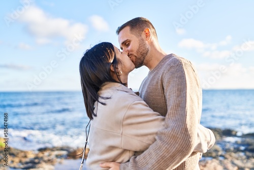 Man and woman couple hugging each other kissing at seaside