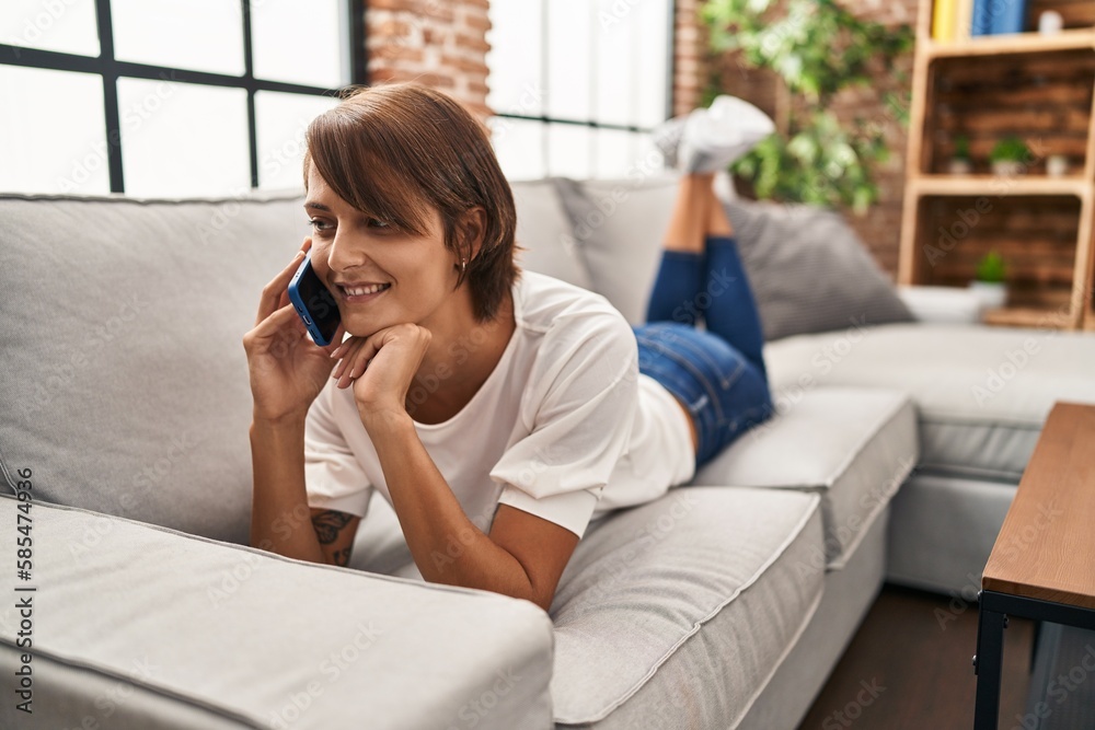 Young beautiful hispanic woman talking on the smartphone lying on sofa at home Young beautiful hispanic woman talking on the smartphone lying on sofa at home