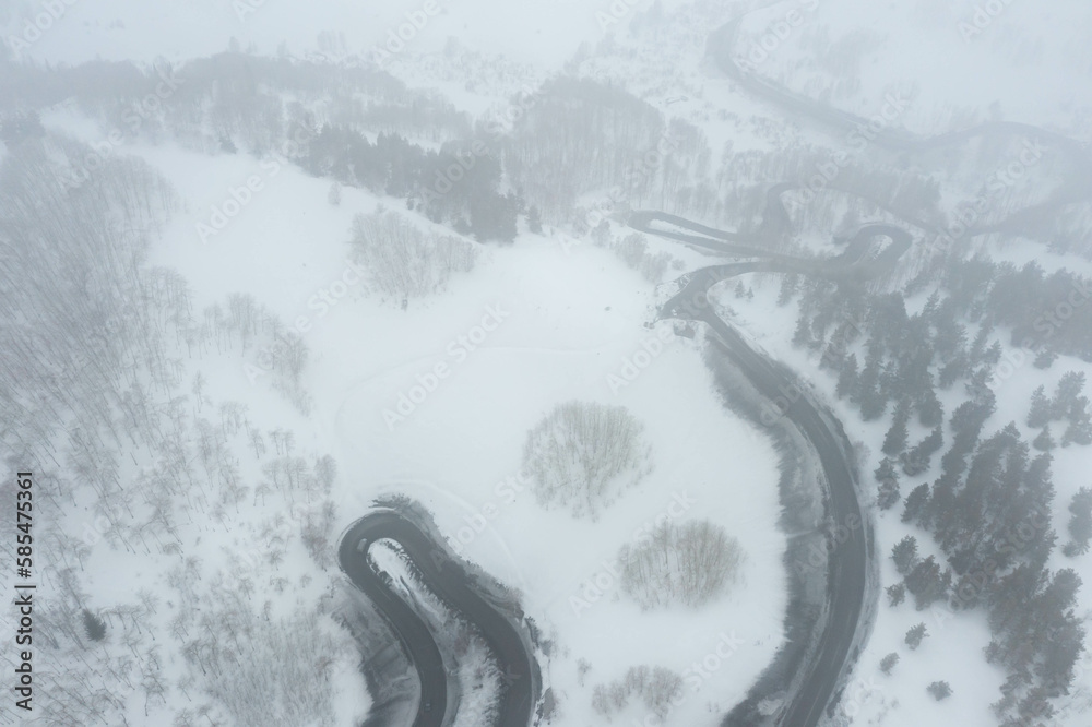 Fototapeta premium A snake shaped pass road in winter photographed from above. Birds eye view
