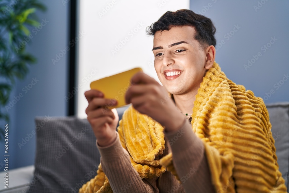 Young non binary man playing video game on smartphone at home Young non binary man playing video game on smartphone at home