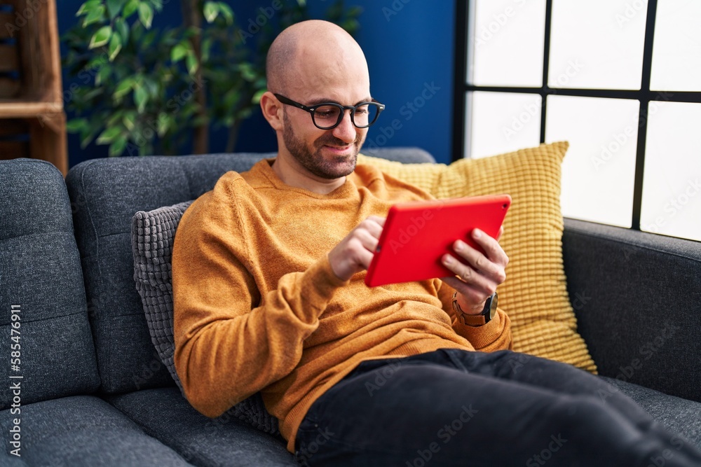 Young man using touchpad sitting on sofa at home Young man using touchpad sitting on sofa at home