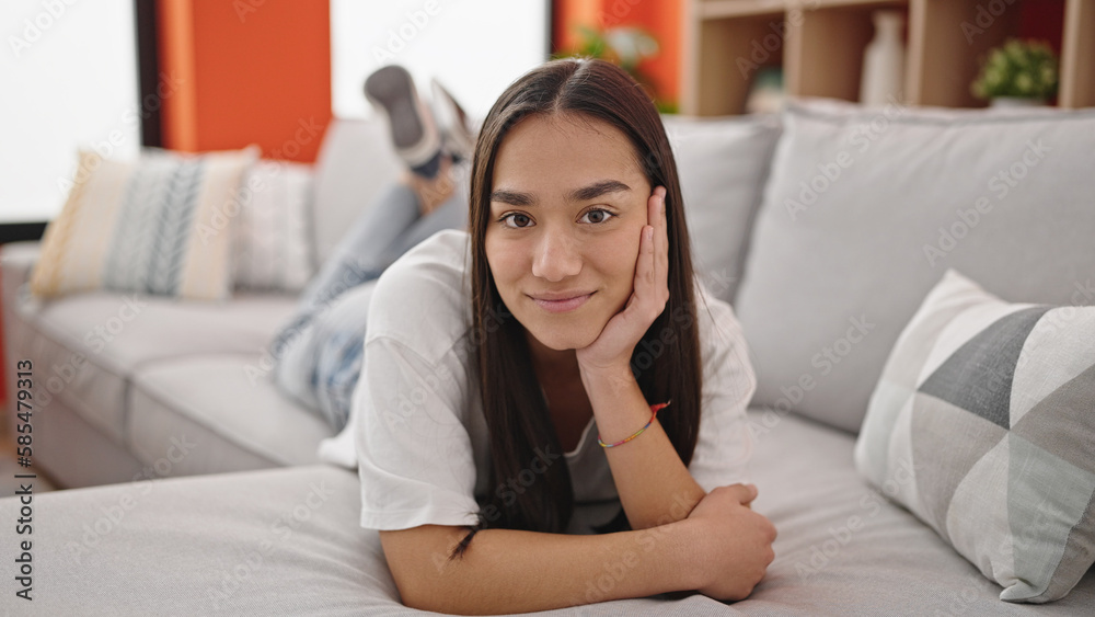 Young beautiful hispanic woman smiling lying on the sofa at home Young beautiful hispanic woman smiling lying on the sofa at home
