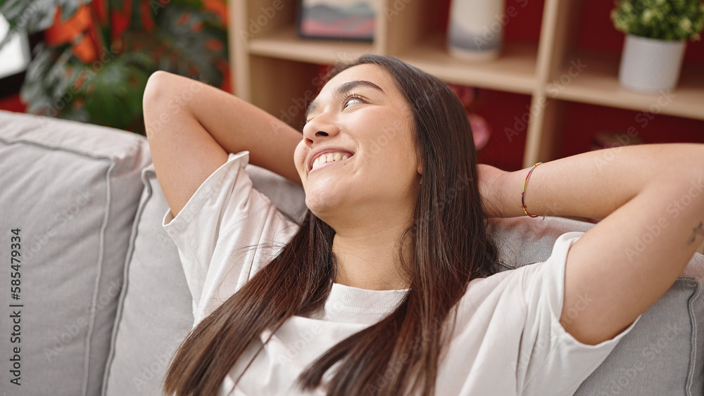 Young beautiful hispanic woman relaxed with hands on head sitting on sofa at home Young beautiful hispanic woman relaxed with hands on head sitting on sofa at home