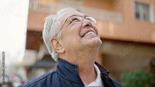 Middle age man with grey hair smiling confident looking up at street