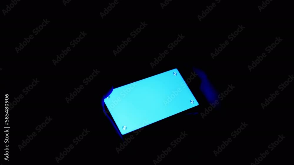 Male Hands Holding Mobile Phone with Green Screen Chroma Key in Dark Room. Close up. Person touching the screen of the smartphone with a finger. Watching videos on phone with a green mockup at night. Male Hands Holding Mobile Phone with Green Screen Chroma Key in Dark Room. Close up. Person touching the screen of the smartphone with a finger. Watching videos on phone with a green mockup at night.