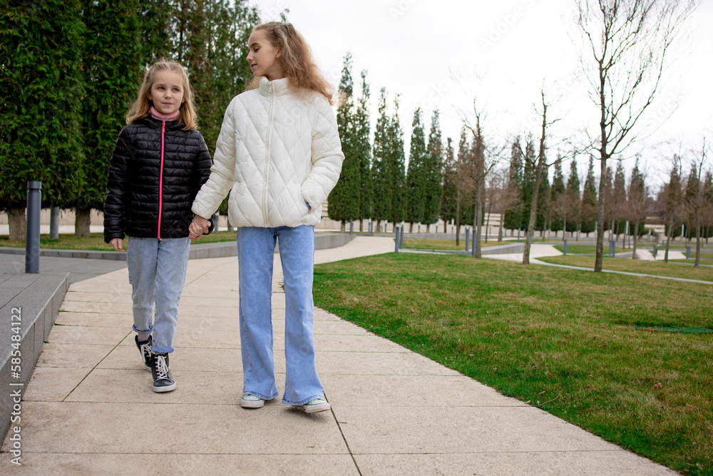 Two little girls sisters walking in the park holding each other's hand. Sincere and trusting relationships between children Two little girls sisters walking in the park holding each other's hand. Sincere and trusting relationships between children