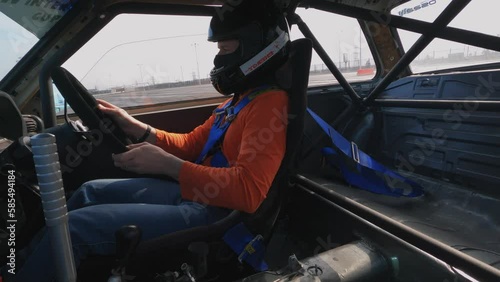 Driver in sports helmet drifts in wheel turns steering wheel entering turn of track, skid pad. Cockpit filming of sports car participation motorsport competition race. Racer in equipment drives car  photo