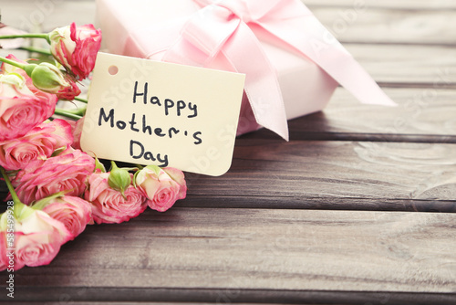 Text Happy Mother's Day with rose flowers and gift box on wooden background