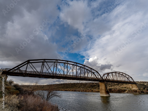 Old Metal bridge spans across the Snake River with dramatic clouds