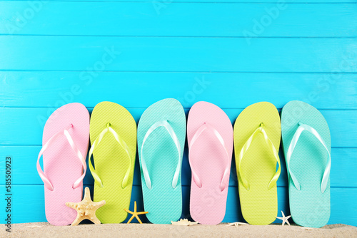 Colorful flip-flops with starfishes on blue wooden background