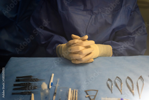 hands of an instrumentalist nurse prepared on a blue sterile field and surgical material for an ophthalmologic retinal surgery.
