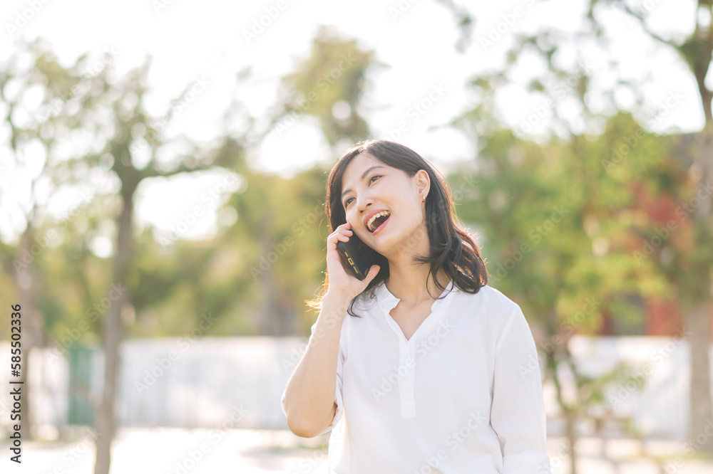 Portrait beautiful young asian woman with smart mobile phone around outdoor nature view in a sunny summer day Portrait beautiful young asian woman with smart mobile phone around outdoor nature view in a sunny summer day