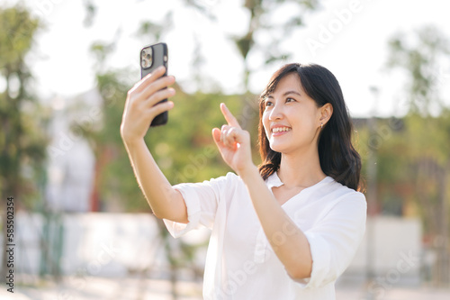 Portrait beautiful young asian woman with smart mobile phone around outdoor nature view in a sunny summer day