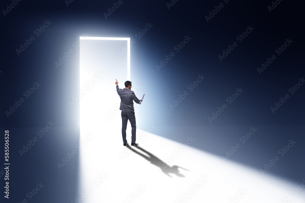 Businessman entering backlit door in escape concept Businessman entering backlit door in escape concept
