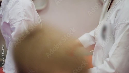 A karate, judo, or tekwondo trainer tightens or ties a white belt on a kimono before training. Slow motion video. A child in a kimono photo