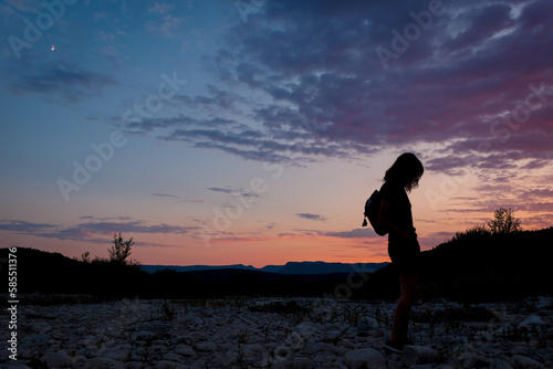 A silhouette of a female traveler standing in the mountains during sunset