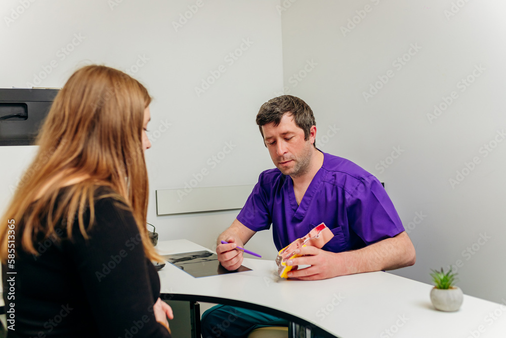 Male Proctologist doctor showing artificial model of human rectum to patient in hospital during consultation Male Proctologist doctor showing artificial model of human rectum to patient in hospital during consultation