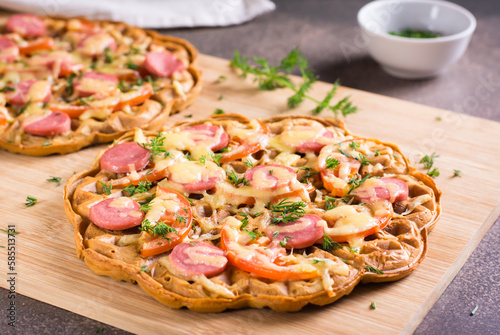 Bild auf Leinwand Waffle pizza with tomatoes, sausages, cheese and herbs on a wooden board