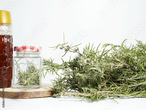 Close up, glass jar with rosemary, next to a container with honey.