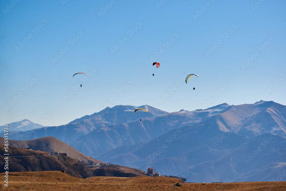 A few paragliders fly between the snow-capped mountains. extreme sports, freedom and beauty of nature A few paragliders fly between the snow-capped mountains. extreme sports, freedom and beauty of nature