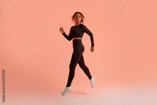 Black female athlete jumping  running  exercising during training over neon studio background  full length