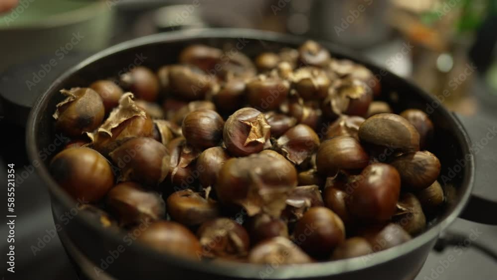 Cooking marrons nuts inside pan stirring with wooden spoon