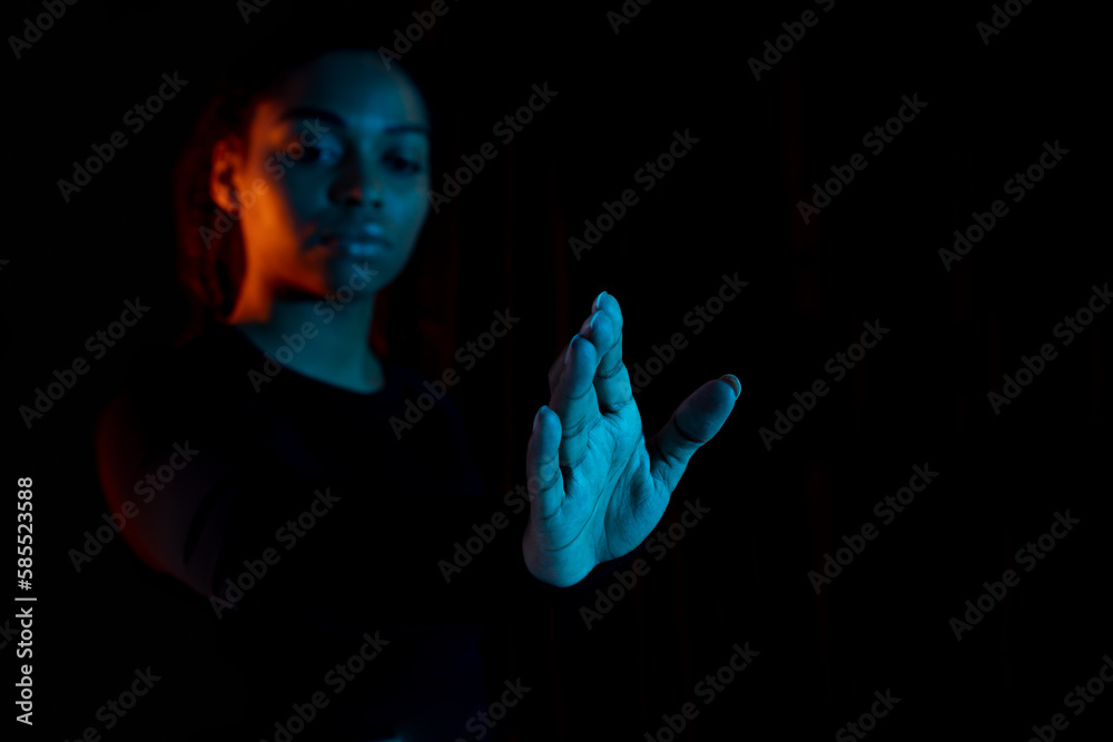 Virtual reality concept. Young african american lady stretching hand and touching invisible touchscreen, neon light Virtual reality concept. Young african american lady stretching hand and touching invisible touchscreen, neon light