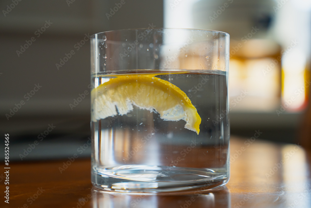 Big slice of lemon in crystal clear water in a glass Big slice of lemon in crystal clear water in a glass