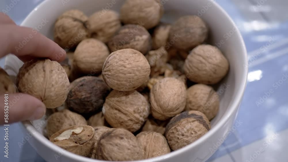 Farmer Hands Putting Walnuts in a Bowl with Collected Nuts on the Table. Close-up. Autumn harvest of ripe, fresh walnuts. Useful healthy food. Brain food. Diet food. Vegetarianism. Walnut shell. 4K. Farmer Hands Putting Walnuts in a Bowl with Collected Nuts on the Table. Close-up. Autumn harvest of ripe, fresh walnuts. Useful healthy food. Brain food. Diet food. Vegetarianism. Walnut shell. 4K.