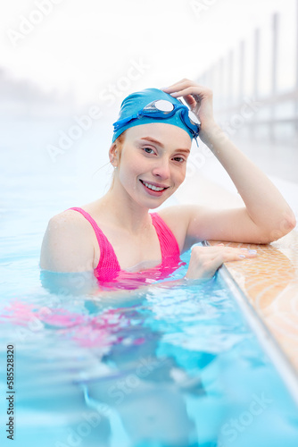 Woman having rest after competition, woman wins the medal, prize in the competition.smiling woman leaning on the edge of pool, touching her cap, posing , looking at the camera. happiness © Roman