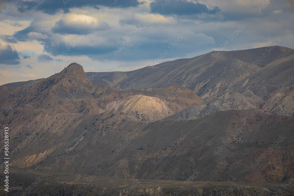 Naklejka premium Arid treeless mountains during the day with spectacular clouds