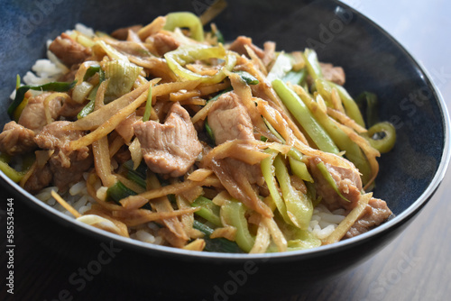 Stir fried pork with ginger, garlic, onion and chillies in a bowl with boiled rice.  