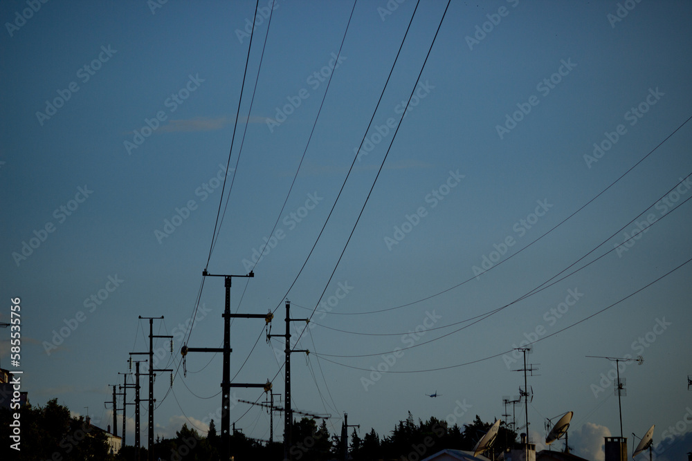 Postes de eletricidade de alta tensão que dão luz à cidade sobre o céu azul
