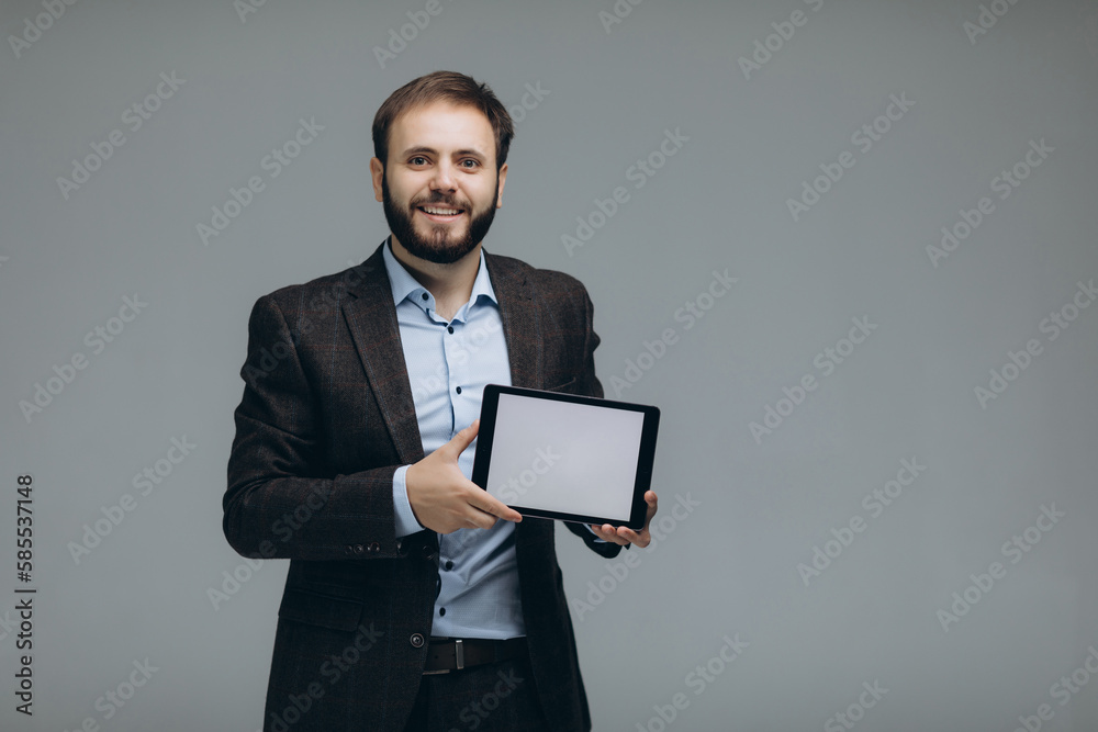 Attractive smiling white collar worker standing on grey background, looking at camera and holding tablet. Attractive smiling white collar worker standing on grey background, looking at camera and holding tablet.