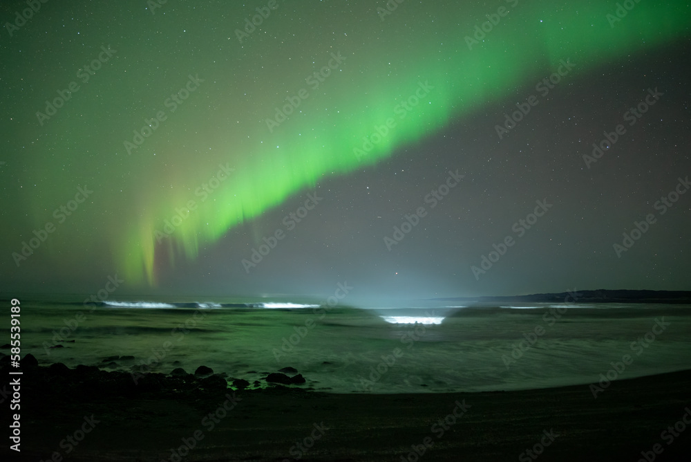 Aurora borealis over illuminated ocean waves Iceland