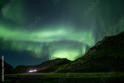 Car driving mountain road under Aurora borealis Iceland