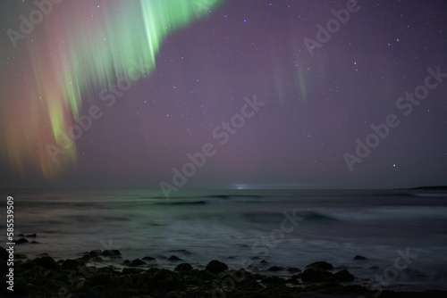 Aurora borealis over ocean framing starry sky, Iceland