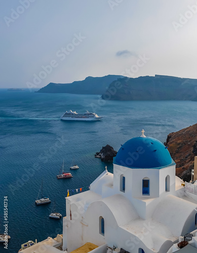 Panoramic view of Church of Agios Nikolaos in Oia town in Santorini. Traditional and famous white houses and churches with blue domes in Aegean sea