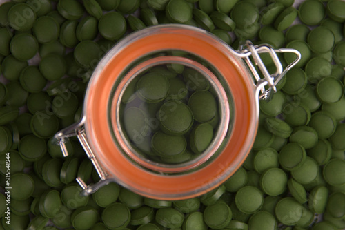 Green tablets of bio chlorella in a glass jar. A health-promoting dietary supplement rich in vitamins. Chlorella vulgaris.