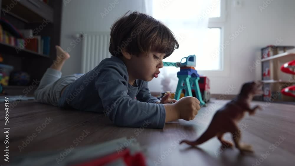 Joyful child playing with toys in bedroom. Little boy laying on floor having fun Joyful child playing with toys in bedroom. Little boy laying on floor having fun