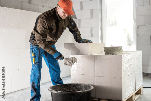 Obraz na plátně Scooping mortar with a spoon mason from the mortar bin